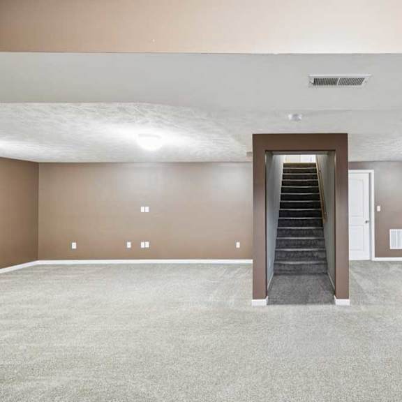 Thumbnail 24 of 26 Finished lower-level family room with carpet flooring, recessed lighting, and central staircase access.