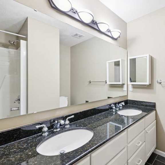 Thumbnail 15 of 26 Double-sink bathroom vanity with granite countertop, large wall mirror, and modern light fixture.