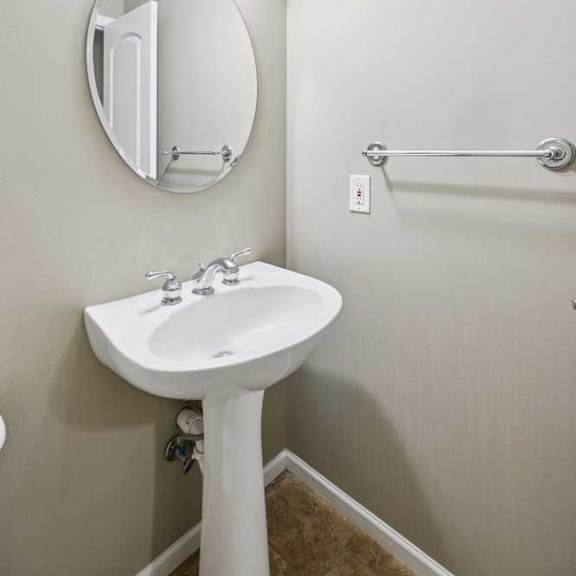 Thumbnail 8 of 26 Half bathroom with pedestal sink, oval mirror, and tile flooring.