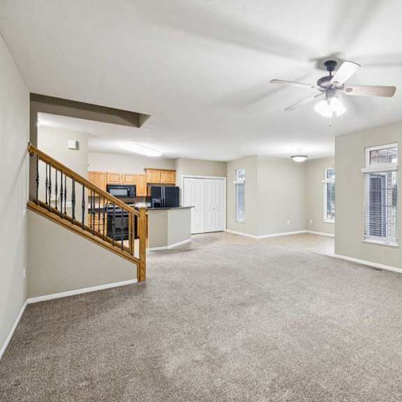Thumbnail 12 of 26 Bright living area with ceiling fan, multiple windows, and open sightlines to kitchen.