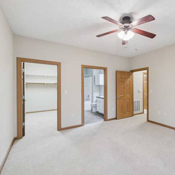 Thumbnail 15 of 20 Primary bedroom with ceiling fan, en-suite bathroom access, and large walk-in closet through separate doorways.