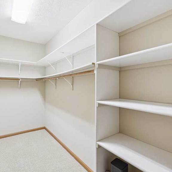 Thumbnail 16 of 20 Walk-in closet with built-in shelving, multiple hanging rods, and carpet flooring for organized storage.