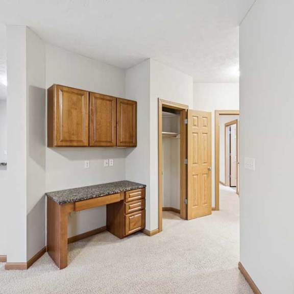 Thumbnail 10 of 20 Living area with built-in desk and upper cabinets, laminate countertop, and open access to hallway and bedrooms.