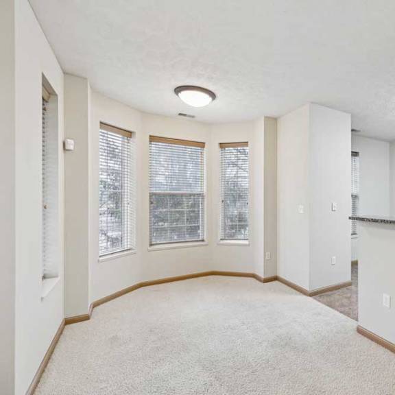 Thumbnail 4 of 20 Open dining area with bay windows, neutral carpet, and breakfast bar overlooking the kitchen.