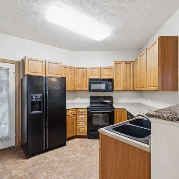 Thumbnail 5 of 20 Kitchen with natural wood cabinets, black appliances, double-basin sink, laminate countertops, and vinyl tile flooring.