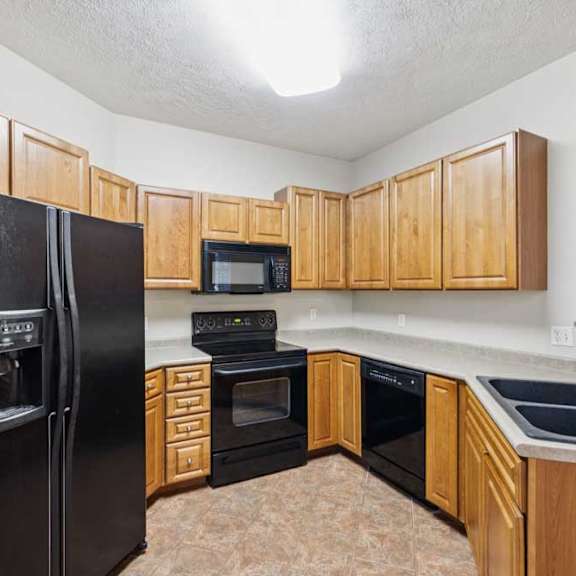 Thumbnail 6 of 20 Corner kitchen layout featuring upper and lower cabinetry, black refrigerator, electric range with microwave, and dishwasher.