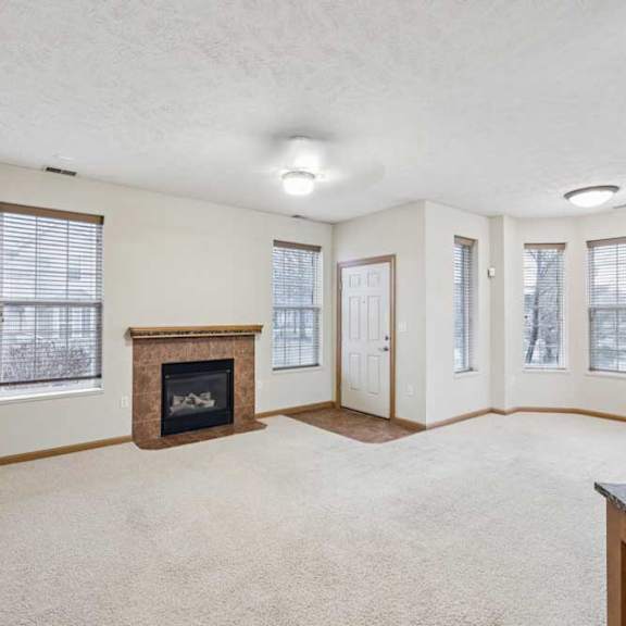 Thumbnail 8 of 20 Spacious living room with gas fireplace, multiple windows for natural light, and neutral carpet.