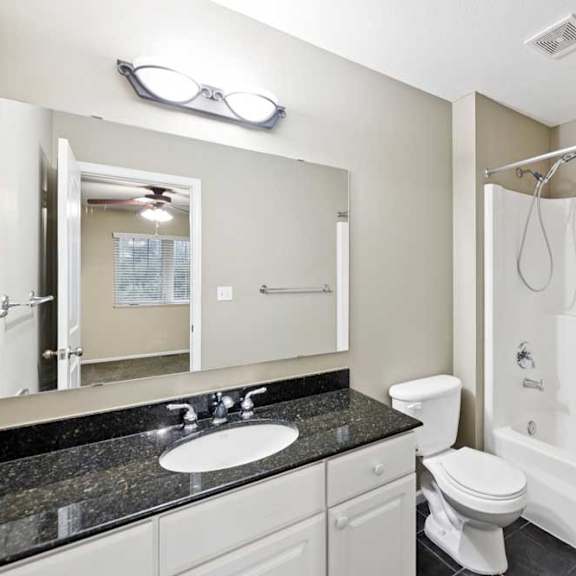 Thumbnail 21 of 25 Full bathroom with single-sink vanity, granite countertop, toilet, and tub and shower combination.