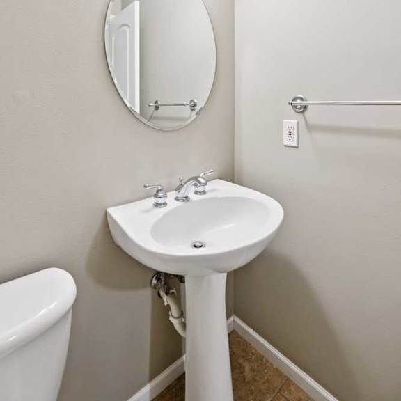 Thumbnail 13 of 25 Half bathroom with pedestal sink, oval mirror, and wall-mounted lighting.