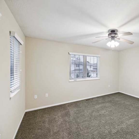 Thumbnail 16 of 25 Large bedroom with neutral carpet, ceiling fan, and single window for natural light.