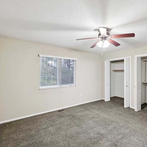 Thumbnail 23 of 25 Primary bedroom with ceiling fan, wide window, and dual closets with built-in shelving.