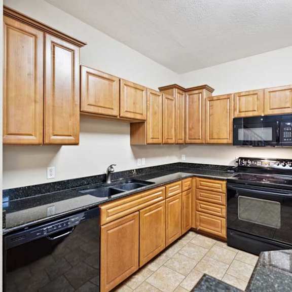Thumbnail 10 of 25 L-shaped kitchen featuring black dishwasher, electric range with microwave, double-basin sink, and tile flooring.