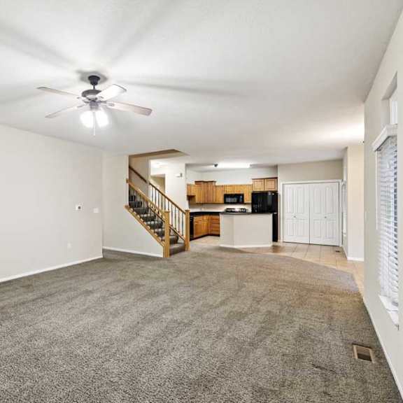 Thumbnail 4 of 25 Large living room with multiple windows, neutral carpet, and open layout to kitchen and dining area.