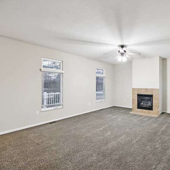 living room with corner gas fireplace, tall windows, and wall-mounted thermostat.