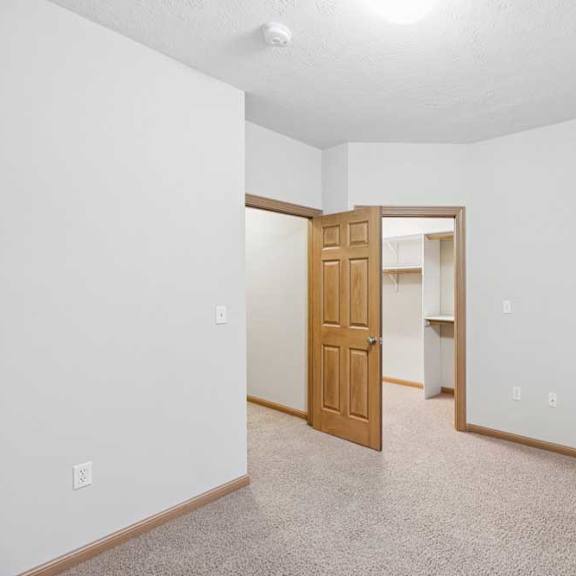 Thumbnail 18 of 21 Bedroom with walk-in closet access and neutral carpeted flooring.