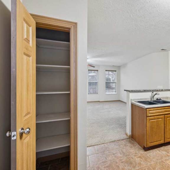 Thumbnail 8 of 21 Pantry closet with built-in shelving off the kitchen and open view to living area.