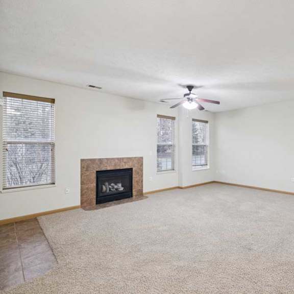 Thumbnail 9 of 21 Open-concept apartment living space with ceiling fan, large windows, and breakfast bar overlooking the kitchen.