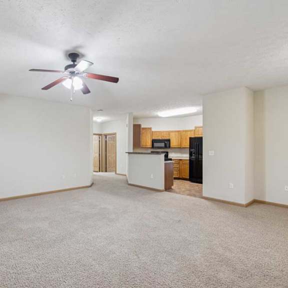 Thumbnail 4 of 21 Expansive living and dining area with carpet flooring and open kitchen layout in the background.