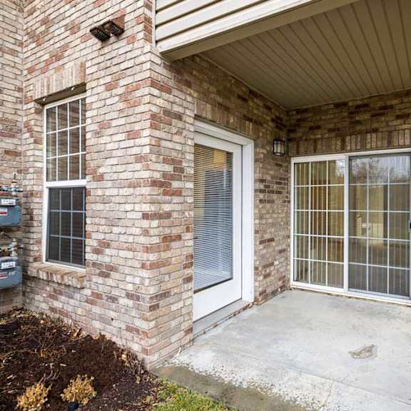 Thumbnail 13 of 21 Covered patio entrance with brick façade, exterior light fixture, and sliding glass door access.