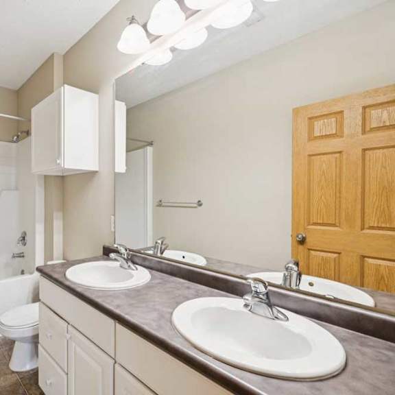 Thumbnail 8 of 21 Full bathroom with double-sink vanity, large mirror, tub and shower combination, and overhead vanity lighting.
