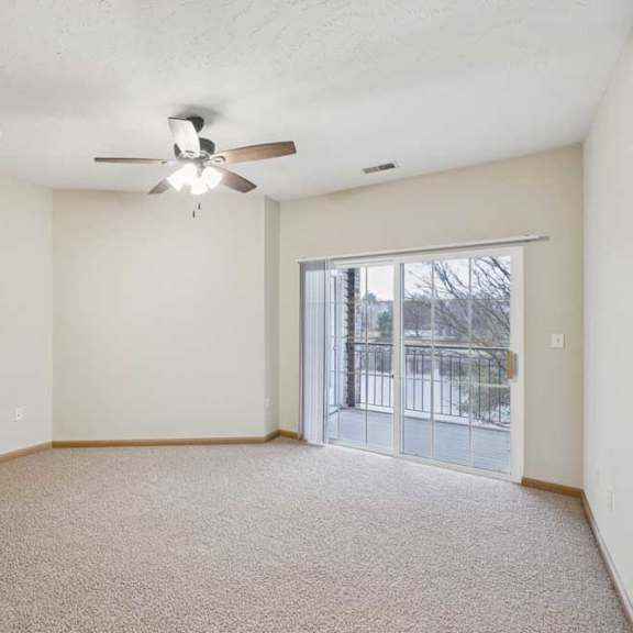Thumbnail 5 of 21 Spacious bedroom with neutral carpet, ceiling fan, and sliding glass door leading to a private balcony with outdoor views.