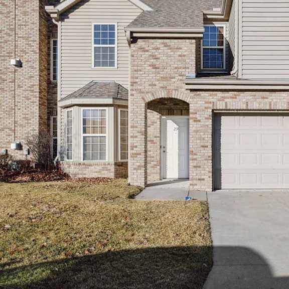 Thumbnail 2 of 21 Brick and siding apartment townhome exterior with attached two-car garage, private entry door, and concrete driveway.