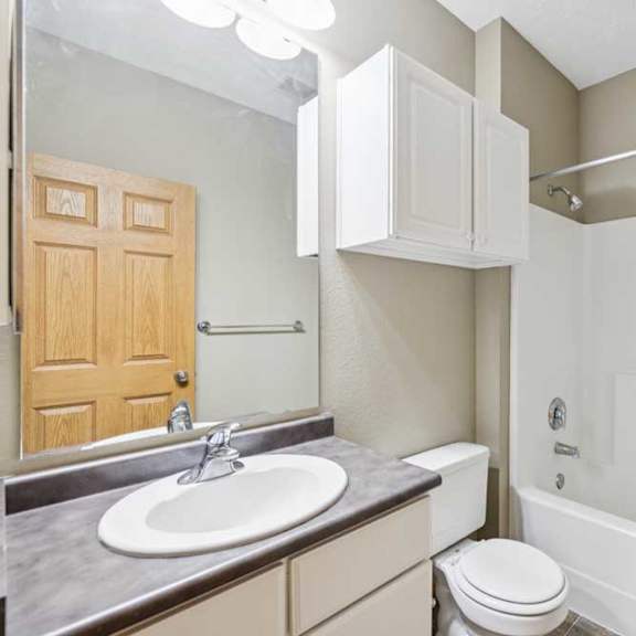 Thumbnail 17 of 20 Full bathroom with tub and shower combination, single-sink vanity, wall cabinet, and large mirror with overhead lighting.