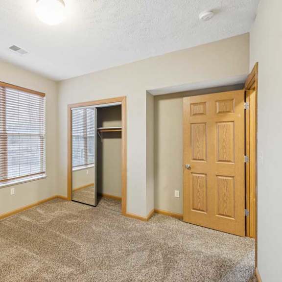 Thumbnail 20 of 20 Bedroom featuring a window with blinds, open closet nook, and neutral carpet in a well-lit apartment space.