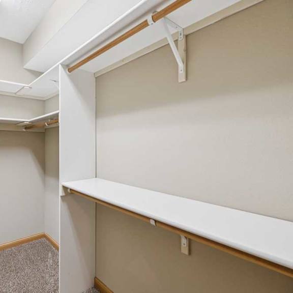 Thumbnail 15 of 20 Walk-in closet with built-in shelving, hanging rods, and carpet flooring for organized storage.
