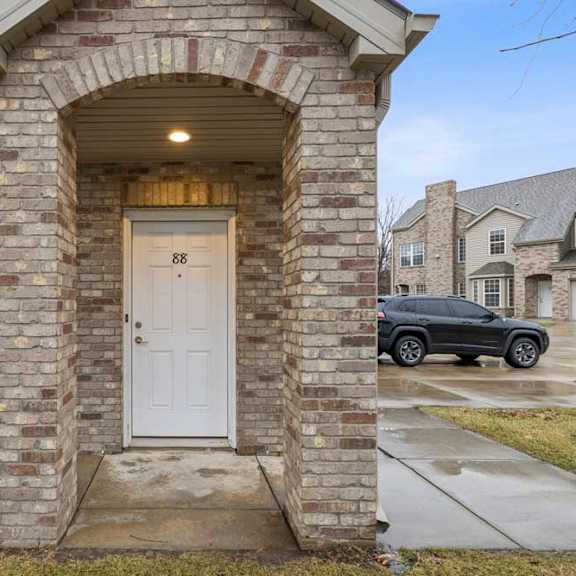 Thumbnail 2 of 20 Brick apartment townhome exterior with covered entry, arched detail, and private front door.