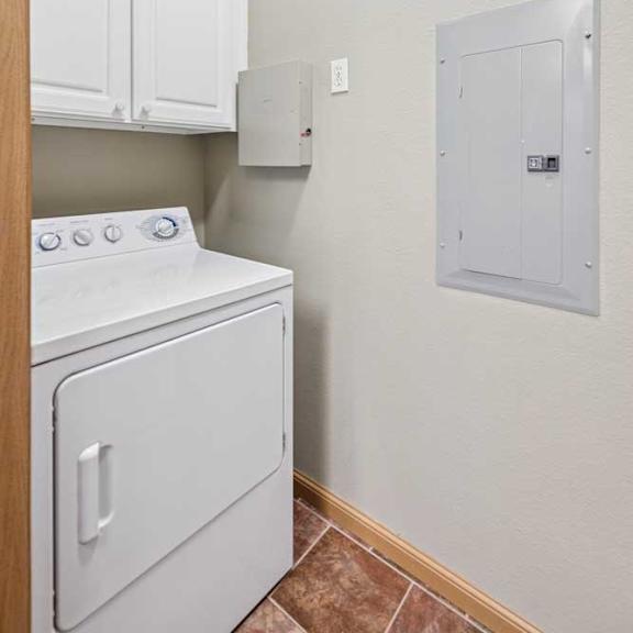 Thumbnail 6 of 20 In-home laundry area with white washer and dryer, upper storage cabinets, and tile flooring.
