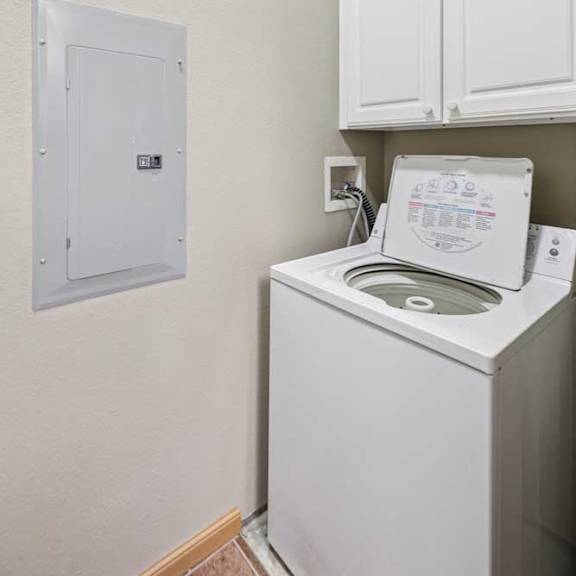Thumbnail 7 of 20 Laundry nook with top-load washer, white cabinetry, and dedicated utility hookups.