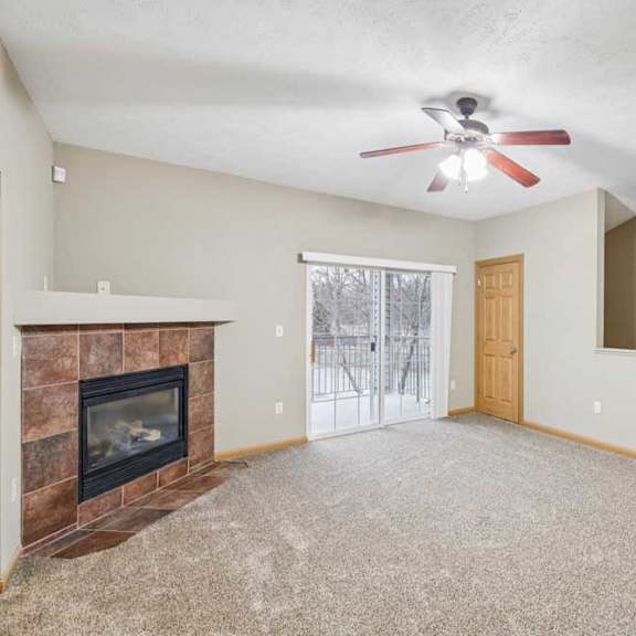 Thumbnail 9 of 20 Spacious living room with ceiling fan, corner tile-surround fireplace, and sliding glass door leading to a private balcony.