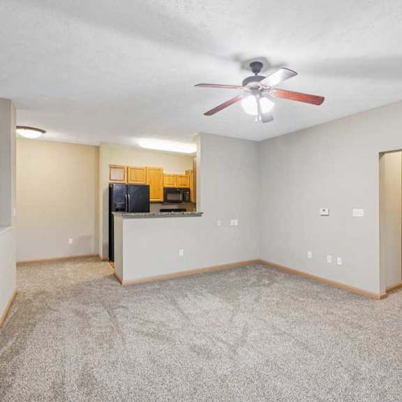 Thumbnail 12 of 20 Bright living area with plush carpet, ceiling fan, fireplace with mantel, and large window with blinds.