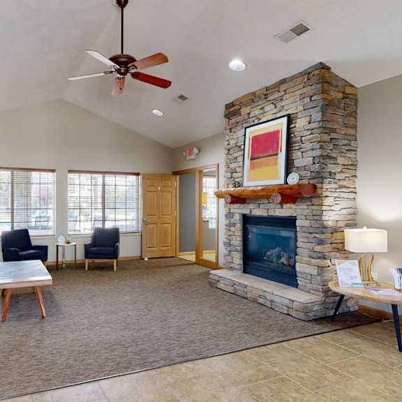 clubhouse living room with a fireplace and a ceiling fan