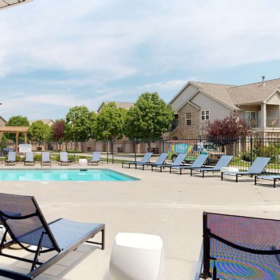 a swimming pool with chaise lounge chairs and trees in the background