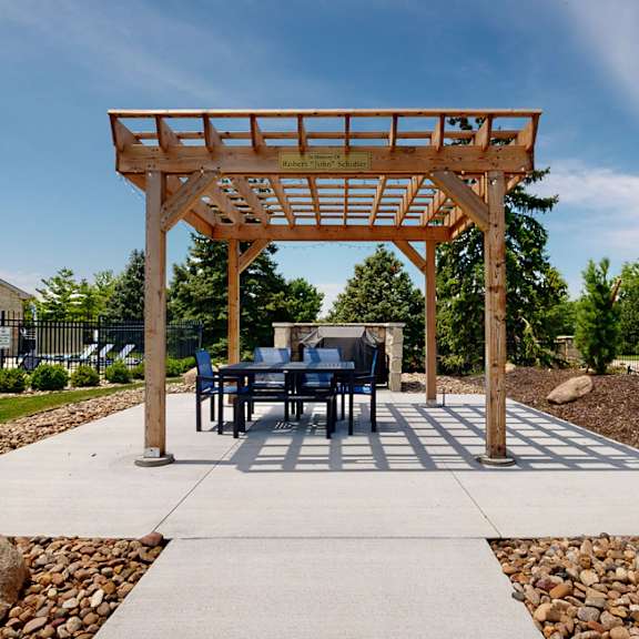 a table and chairs under a wooden pergola