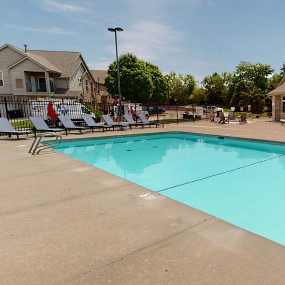 a swimming pool with lounge chairs and the clubhouse building in the background