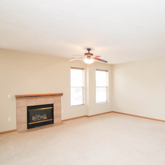 Thumbnail 3 of 12 an empty living room with a ceiling fan and a fireplace