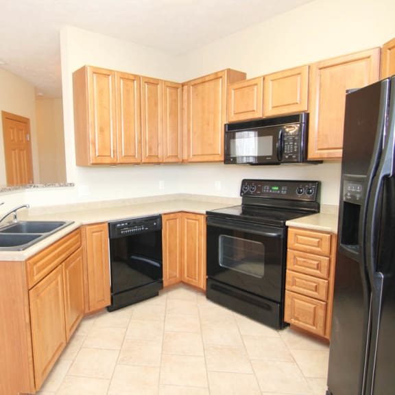 Thumbnail 5 of 12 a kitchen with black appliances and wooden cabinets