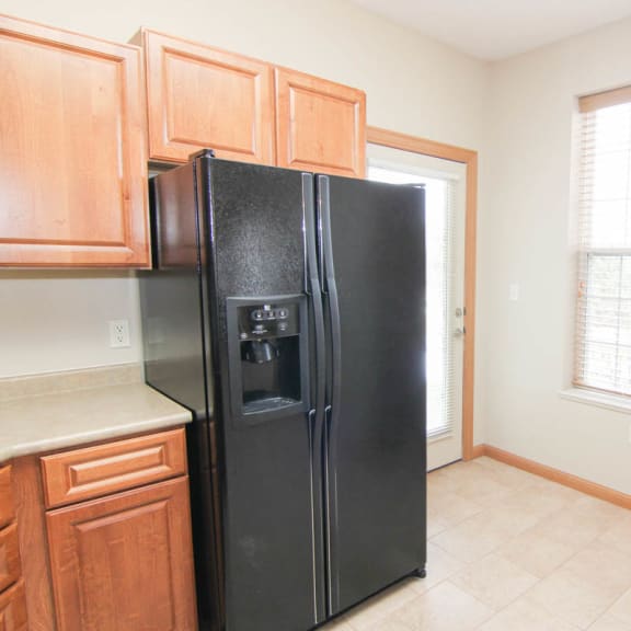 Thumbnail 6 of 12 a kitchen with a black refrigerator and wooden cabinets