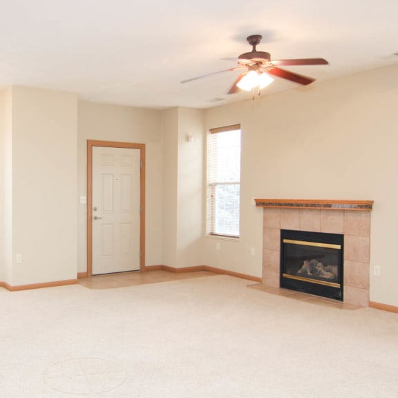 Thumbnail 2 of 12 an empty living room with a fireplace and a ceiling fan