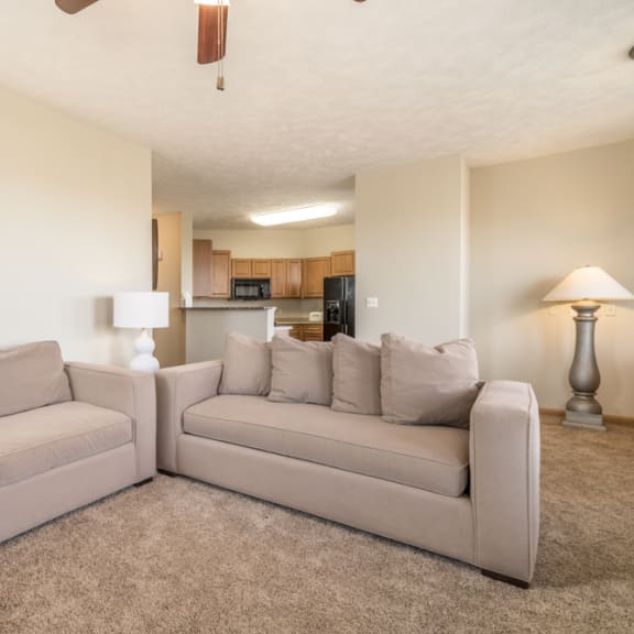 Thumbnail 5 of 12 a living room with a couch and a chair and a kitchen