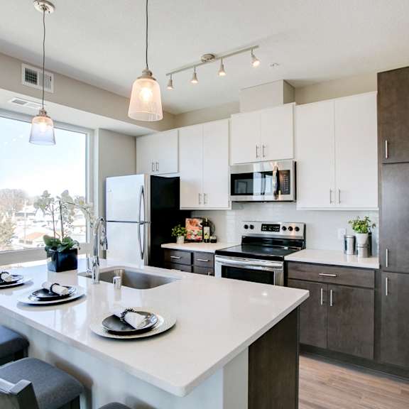 Thumbnail 7 of 15 View of kitchen with white and dark contemporary cabinets and quartz countertops at The Central apartments near downtown Minneapolis MN 55408