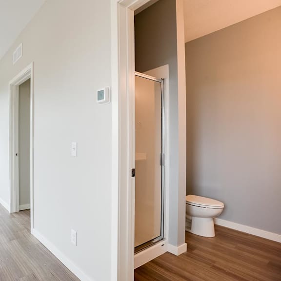Thumbnail 5 of 5 View looking into bathroom with standup shower and toilet and living room with large window