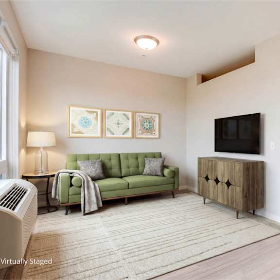 Thumbnail 5 of 7 A living room with a green couch and a television.