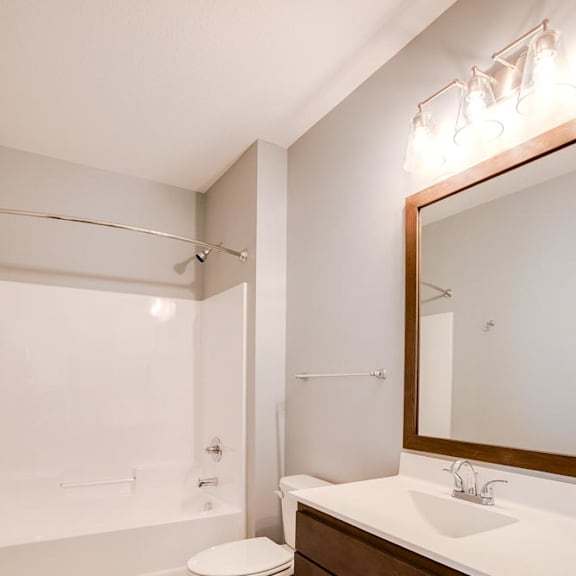 Thumbnail 5 of 5 A white toilet sits in a bathroom with a wooden floor and brown cabinets.