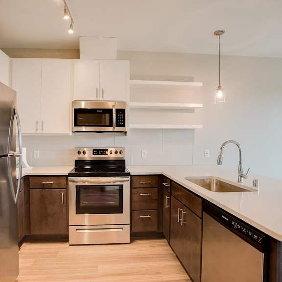 Thumbnail 3 of 5 A modern kitchen with a stainless steel refrigerator and a stove top oven.