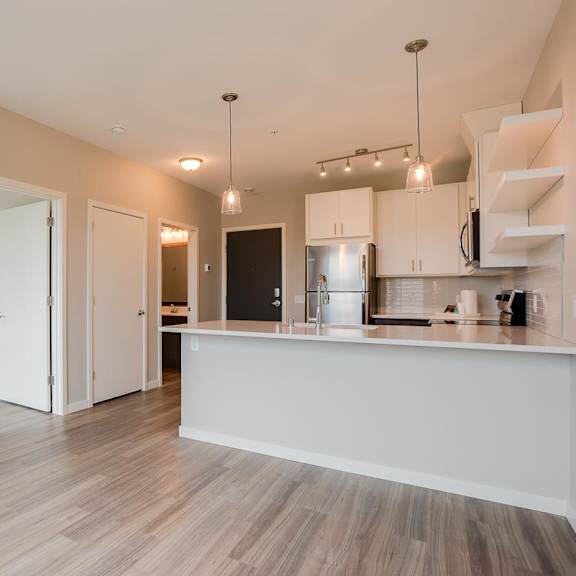 Thumbnail 4 of 5 A kitchen with a white counter and wooden floors.