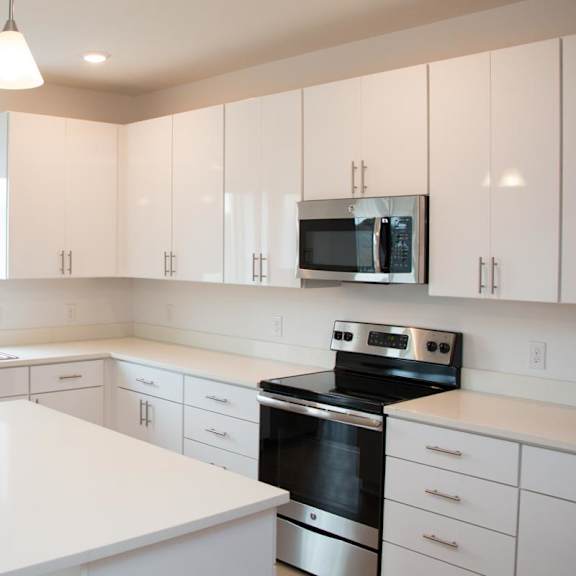 Thumbnail 4 of 8 A spacious kitchen with white cabinets and stainless steel appliances.